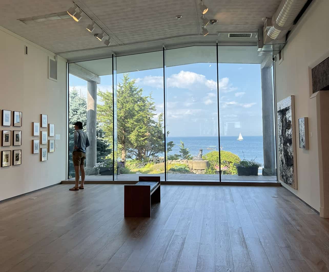 a man near a large glass window looking at art hanging on the wall