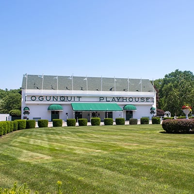 a white building with a green awning, green grass and blue sky